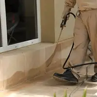General pest control technician spraying exterior perimeter around a home in Kansas City, KS